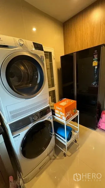 Detached House for rent in Prawet, Bangkok - Laundry zone with stacked washer and dryer next to a tall refrigerator.