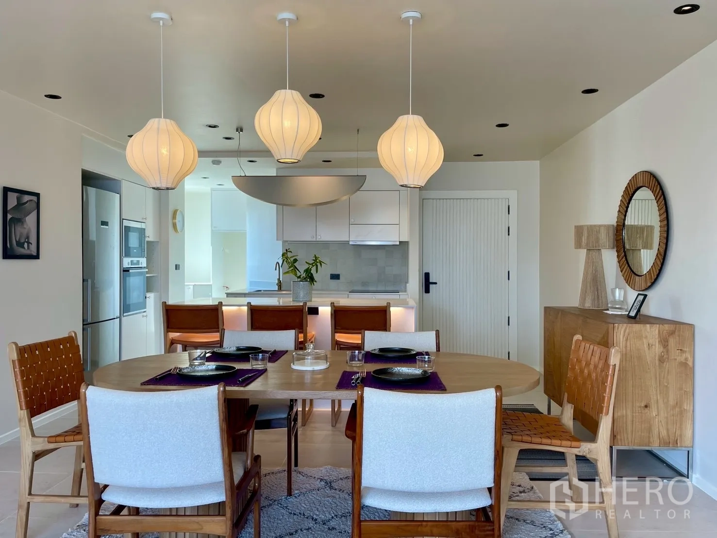 Condominium for sale in Watthana, Bangkok - Dining area with oval table and trio of pendant lights near the kitchen.