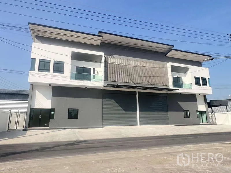 คลังสินค้า ให้เช่าหรือขาย - หน้าตาโกดังสองชั้นสไตล์โมเดิร์น มีประตูม้วนคู่ ระเบียง และลานหน้ากว้าง