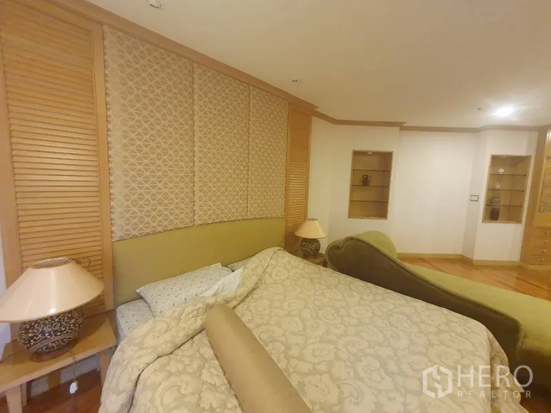 Condominium for rent in Bang Kho Laem, Bangkok - Master bedroom with upholstered headboard, feature wall panels, bedside lamps and built-in shelving.