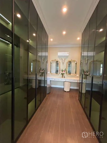 Detached House for sale in Bang Kapi, Bangkok - Walk-in closet corridor with tinted glass wardrobes and mirrored vanity.