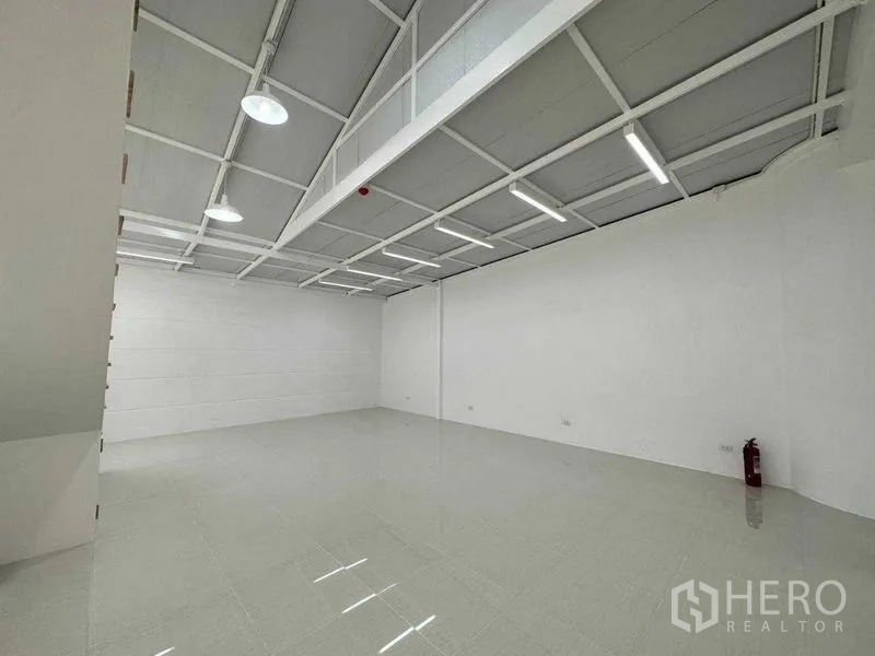 Office Space for rent or sale in Khlong Toei, Bangkok - Open-plan white office floor with glossy tiles, LED strip lights and a fire extinguisher.