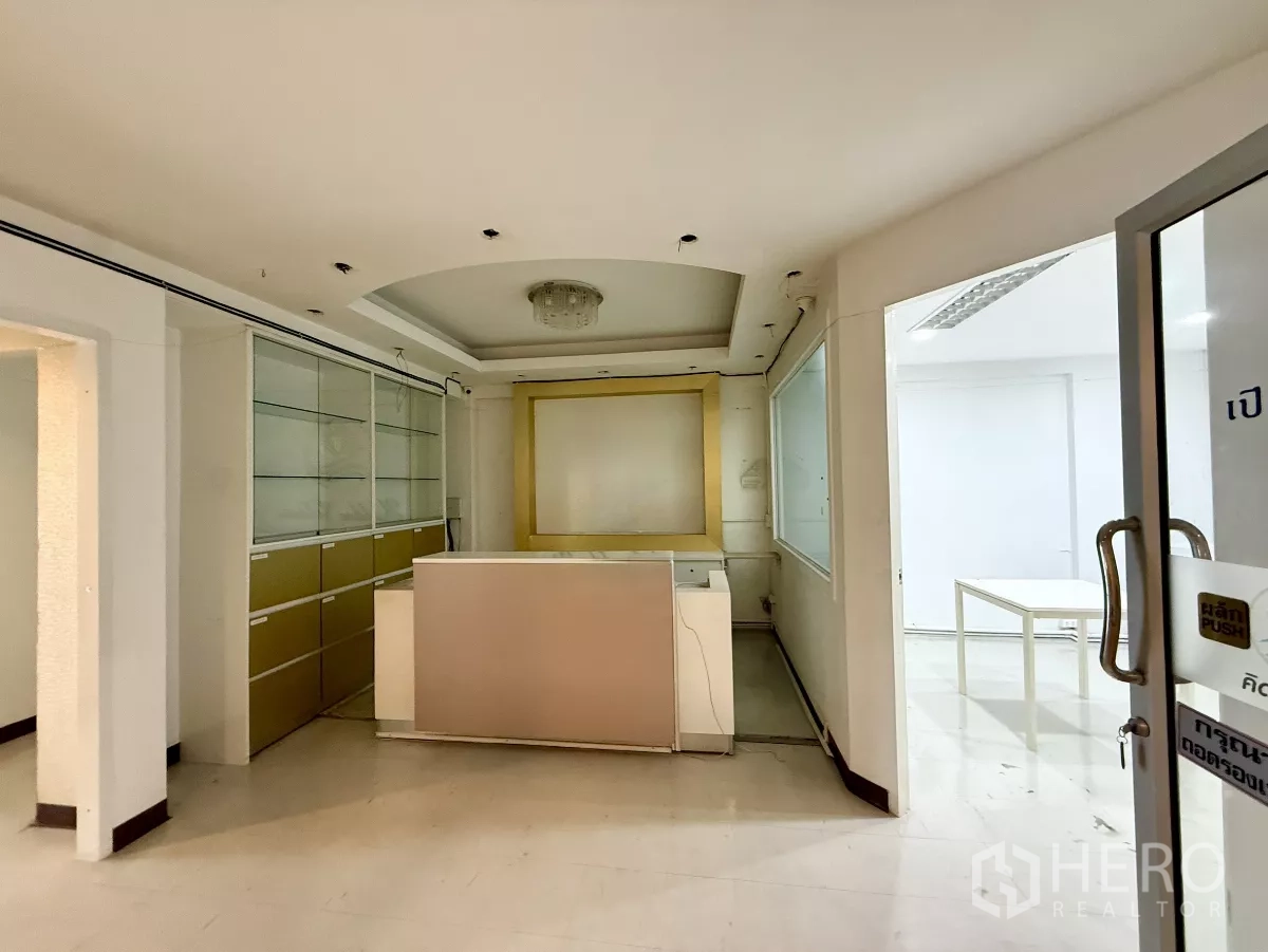 办公空间 出租在Din Daeng, Bangkok - 接待区，带前台与内置玻璃柜，玻璃门与浅色装饰。