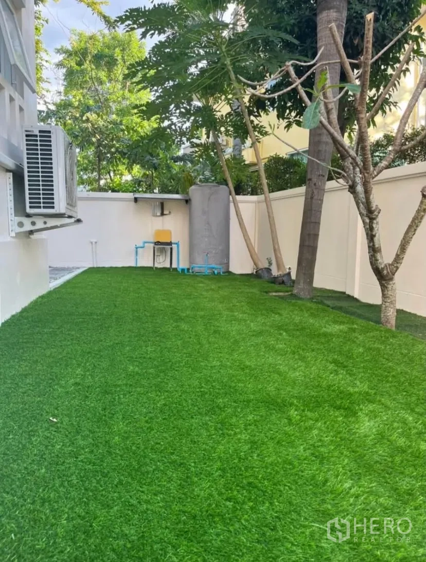 独立式住宅 出租或出售在Lat Phrao, Bangkok - 后院草坪，树荫与围墙环绕。