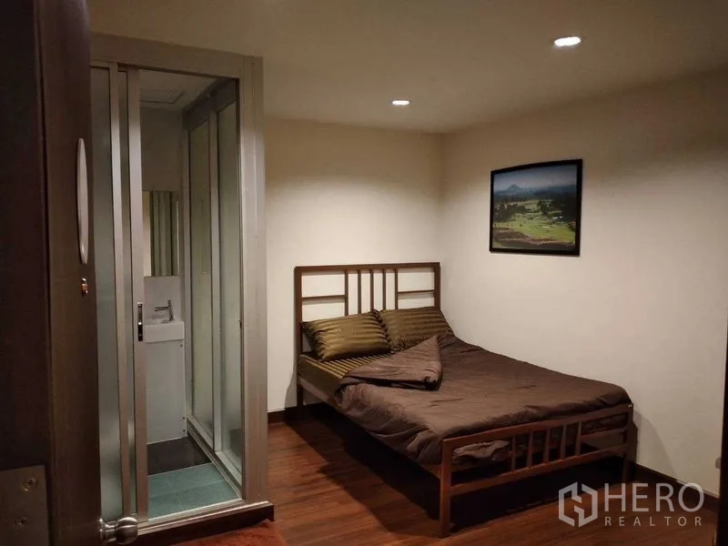 อาคารพาณิชย์ ให้เช่าในWatthana, Bangkok - ห้องนอนขนาดกะทัดรัด เตียงไม้ ผ้าปูสีน้ำตาล พร้อมห้องน้ำในตัวหลังประตูกระจกบานเลื่อน.