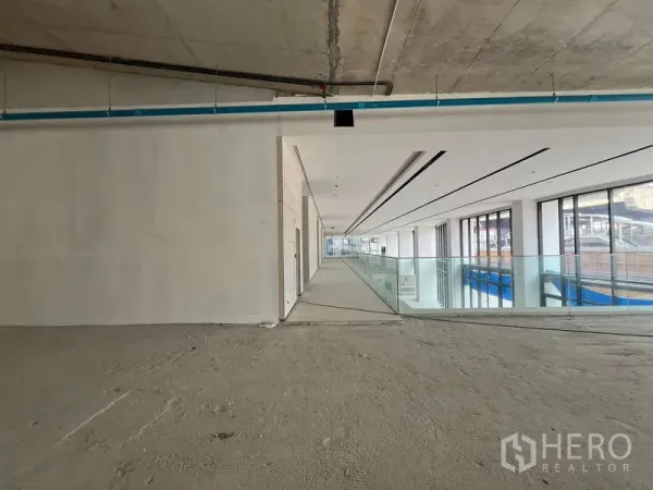 พื้นที่ขายปลีก ให้เช่า - โถงอาคารรีเทลพร้อมราวกันตกกระจกและกระจกเต็มบาน นำไปสู่หน้าร้านที่ยังไม่ตกแต่ง