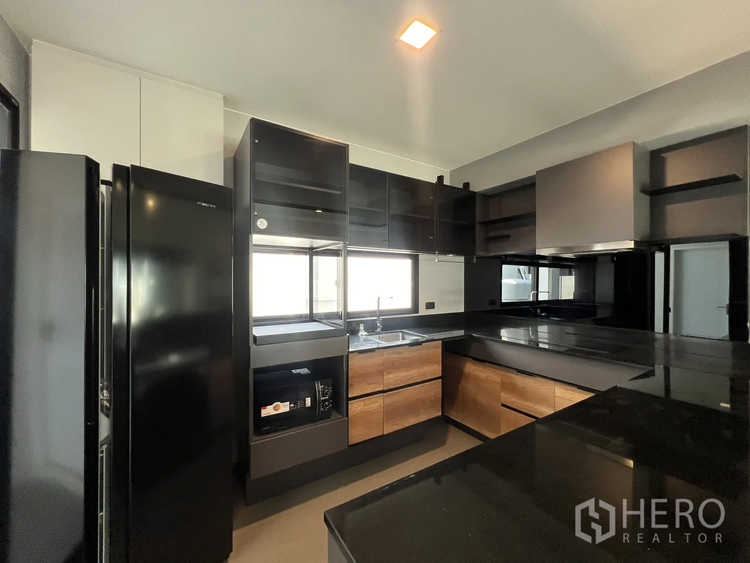 Detached House for rent in Bang Phli, Samut Prakan - Kitchen with ample storage, black appliances and a window above the sink.