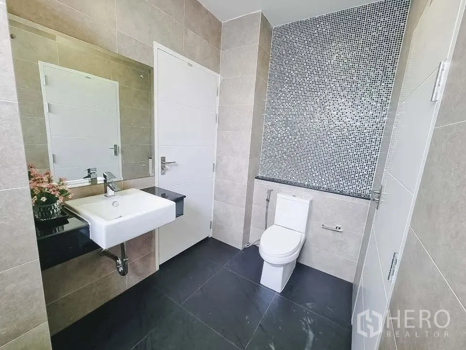 Detached House for rent or sale in Bang Phli, Samut Prakan - Bathroom with mosaic accent wall, toilet, and wall-mounted mirror.