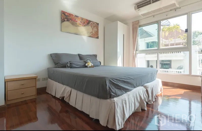 Condominium for rent in Pathum Wan, Bangkok - Bright master bedroom with queen bed and large corner windows letting in city light.
