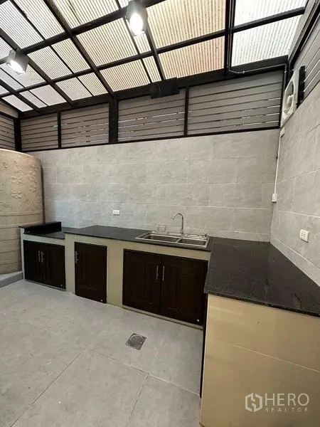 Townhouse for rent in Chom Thong, Bangkok - Covered Thai kitchen with black granite countertops, double sink and tiled walls.