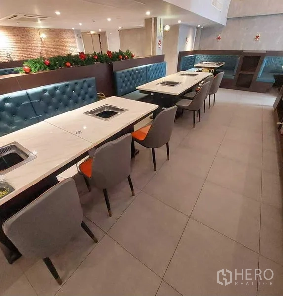 零售空间 出租在Watthana, Bangkok - 用餐区，蓝色卡座与带嵌入式烤炉的大理石桌。