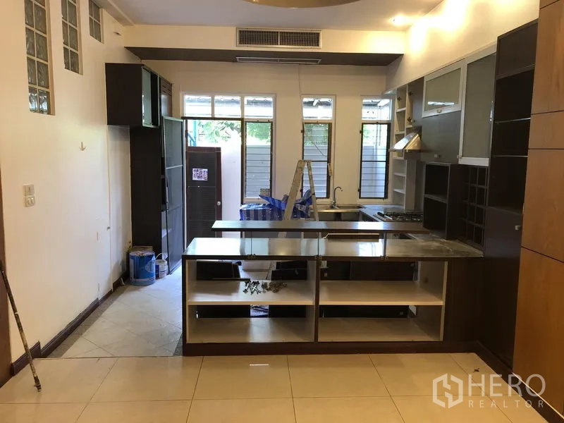 Townhouse for rent or sale in Watthana, Bangkok - Spacious kitchen with an island counter, built-in cabinetry and large windows, shown during light renovation.