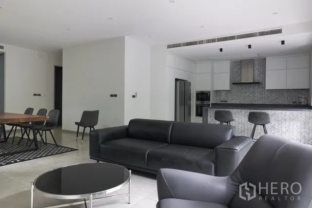 ทาวน์เฮาส์ ขายในWatthana, Bangkok - โถงรับแขกและครัวแบบโอเพ่นแพลน โซฟาหนังสีดำและโต๊ะทานอาหาร