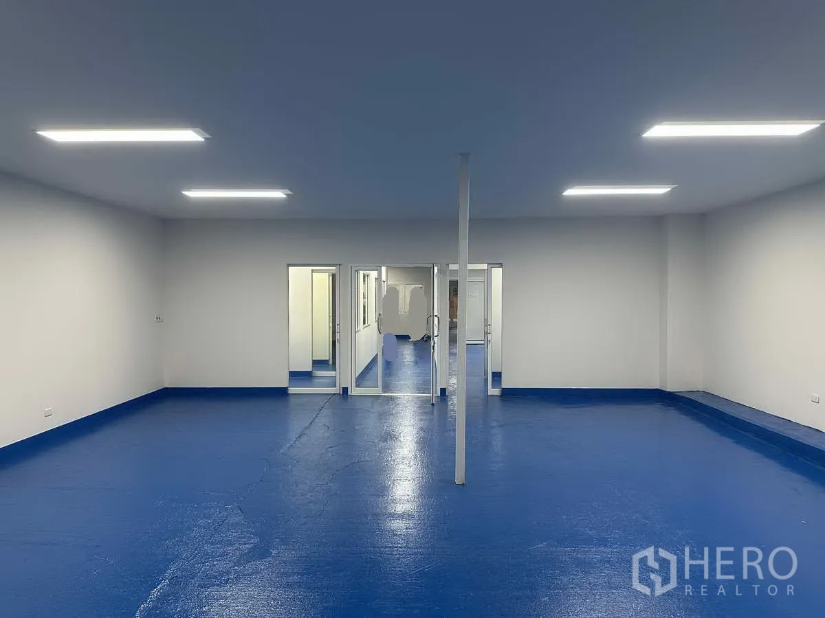 Warehouse for rent in Pak Kret, Nonthaburi - Spacious open room with blue sanitary flooring and glass doors leading to controlled rooms.