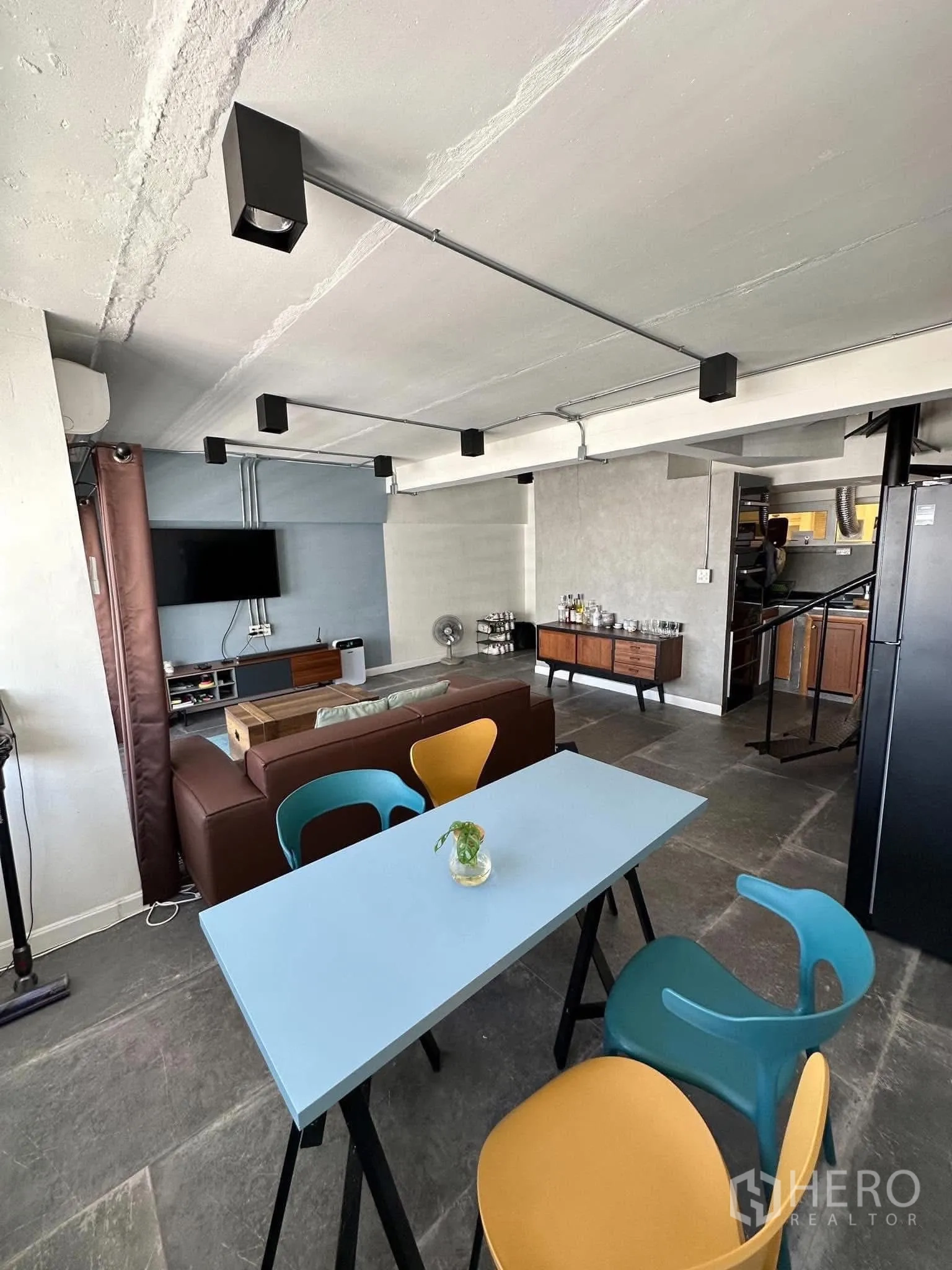 คอนโด ให้เช่าในWatthana, Bangkok - ชุดโต๊ะรับประทานอาหารสีสันสดใสข้างโซนพักผ่อน พร้อมทีวีติดผนังและไฟสไตล์มินิมอล