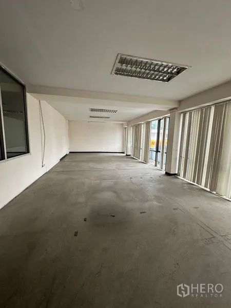Warehouse for rent in Suan Luang, Bangkok - Empty upper-floor room with large windows and vertical blinds, ideal for office or storage.