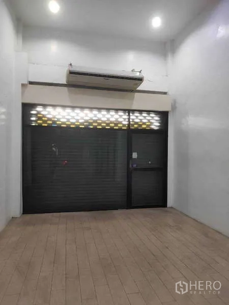 店屋 出售在Phra Khanong, Bangkok - 正面卷闸门与玻璃入口，层高挑空。