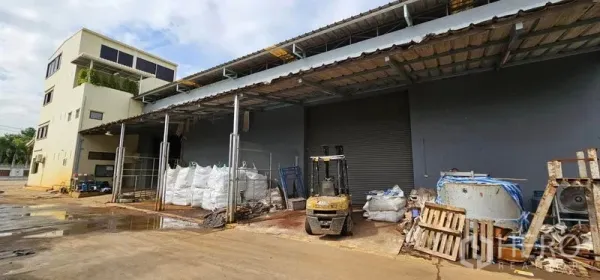 Warehouse for rent in Bang Kruai, Nonthaburi - Covered loading bay with roller shutter, forklift and pallet storage at the warehouse exterior.