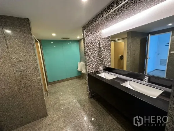 Office Space for rent - Modern office restroom with granite floors, mosaic mirror wall, double sinks and a turquoise glass partition.