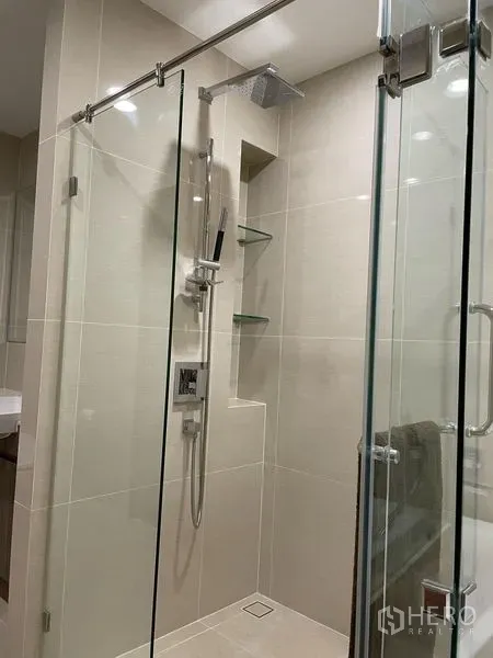 公寓 出租在Bang Na, Bangkok - 玻璃淋浴间特写，顶喷花洒与壁龛置物架。
