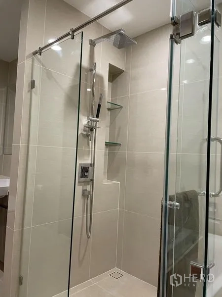 公寓 出租在Bang Na, Bangkok - 玻璃淋浴间特写，顶喷花洒与壁龛置物架。
