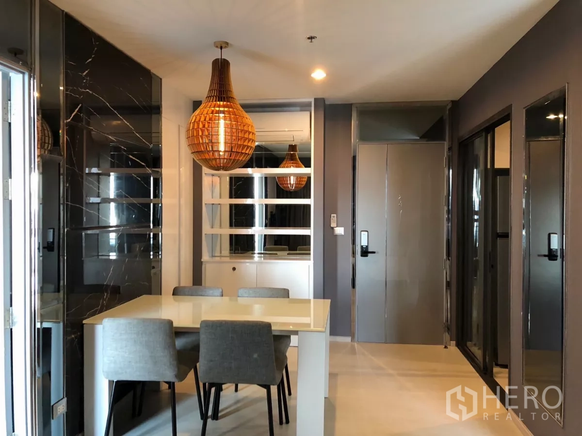 Condominium for rent in Khlong Toei, Bangkok - Dining area with white table, four chairs and a warm pendant light.