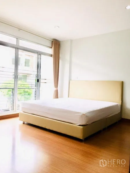 联排别墅 出租在Prawet, Bangkok - 主卧木地板，推拉门通向阳台，采光良好。