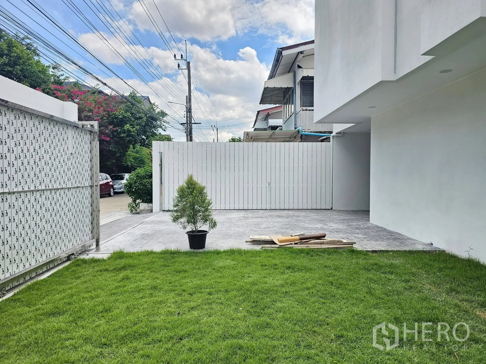 บ้านเดี่ยว for sale in Lat Phrao, Bangkok - ลานหน้าบ้านมีสนามหญ้าและทางรถยนต์ลาดคอนกรีตหลังประตูรั้วเลื่อน