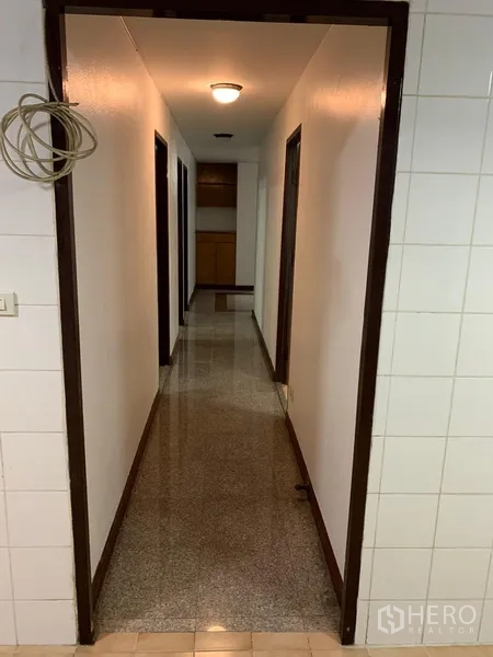 Condominium for rent in Sathon, Bangkok - Long interior corridor with overhead lights leading to the bedrooms and storage.