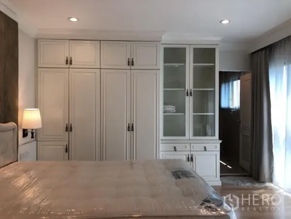 公寓 出租或出售在Sathon, Bangkok - 卧室整面内置衣柜与玻璃展示柜，通往套内卫浴。