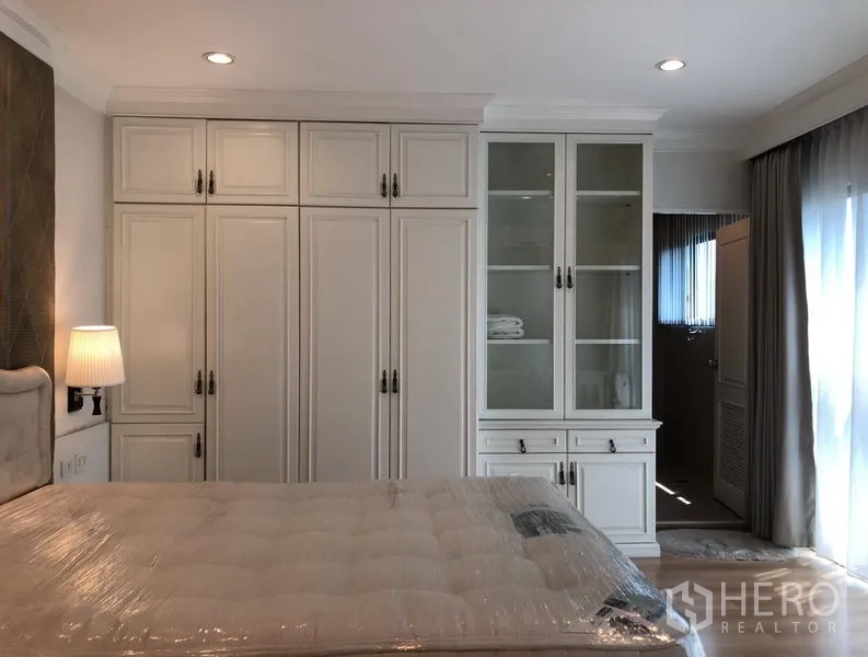 公寓 出租或出售在Sathon, Bangkok - 卧室整面内置衣柜与玻璃展示柜，通往套内卫浴。