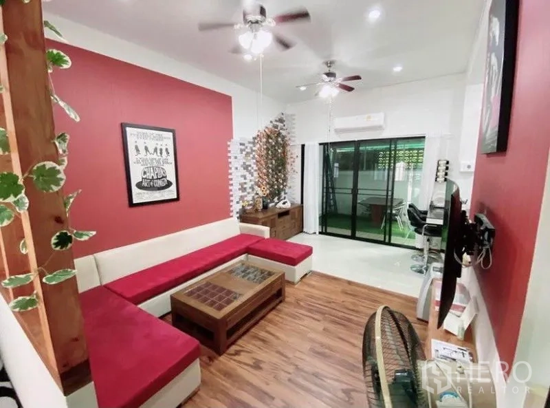 Townhouse for rent in Wang Thonglang, Bangkok - Cozy lounge with L-shaped sofa, ceiling fans, wood flooring, and access to the terrace.