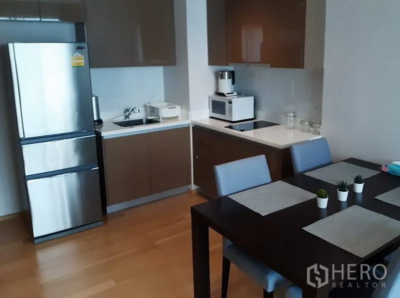 คอนโด ให้เช่าในKhlong Toei, Bangkok - ครัวคอนโดสมัยใหม่ ตู้ลอยรูปตัวแอล ตู้เย็นสแตนเลส เตา และโต๊ะกินข้าว 4 ที่