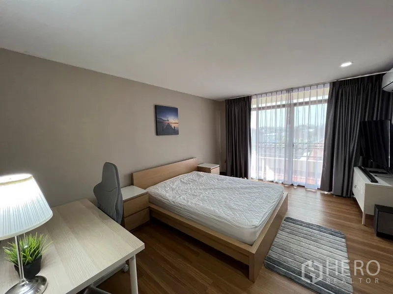 ทาวน์เฮาส์ ให้เช่าหรือขายในSuan Luang, Bangkok - ห้องนอนอบอุ่นมีโต๊ะทำงาน ทางออกสู่ระเบียง และวิวเมืองผ่านผ้าม่านโปร่ง