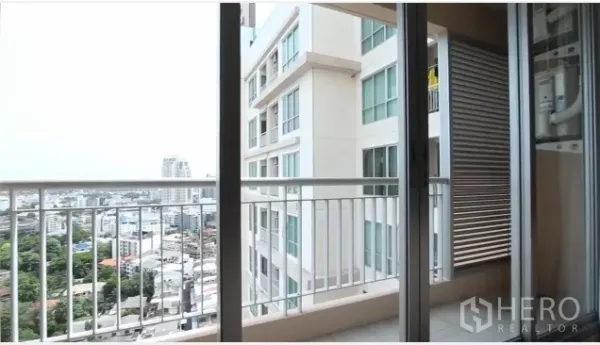 Condominium for rent in Watthana, Bangkok - Balcony with sliding glass doors and open city view overlooking a neighboring building near BTS Phra Khanong.