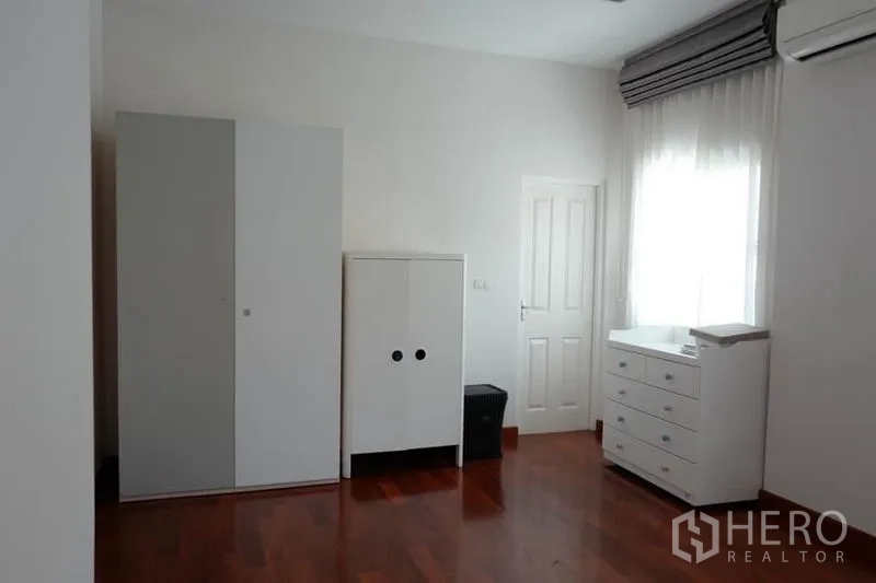 Detached House for sale in Pak Kret, Nonthaburi - Air-conditioned bedroom with wooden floors and white wardrobes.