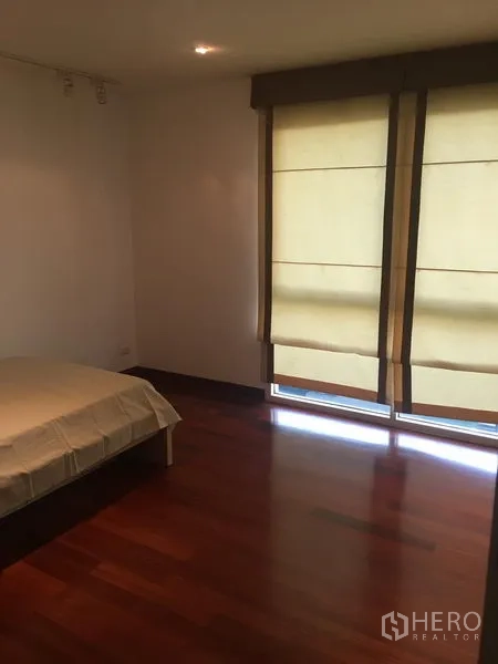 Condominium for rent or sale in Watthana, Bangkok - Guest bedroom with floor-to-ceiling blinds, wood flooring and soft natural light.