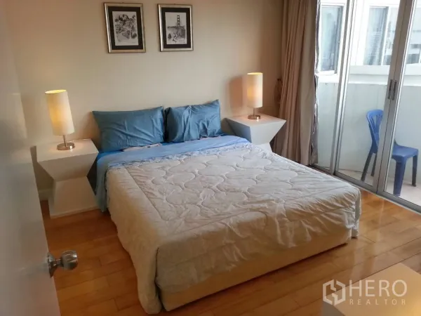 Condominium for rent in Ratchathewi, Bangkok - Bedroom with double bed, bedside lamps and a sliding glass door to the balcony.