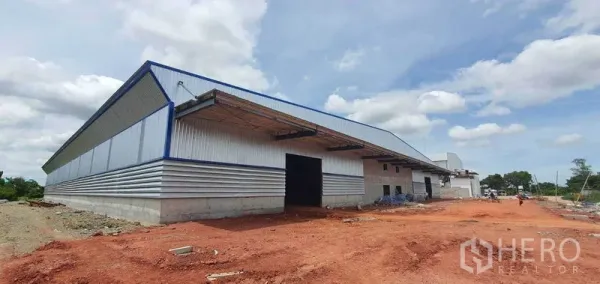 Factory for rent in Mueang Samut Sakhon, Samut Sakhon - Angled view of modern factory exterior with roller shutter doors, canopy awnings, and open yard area.