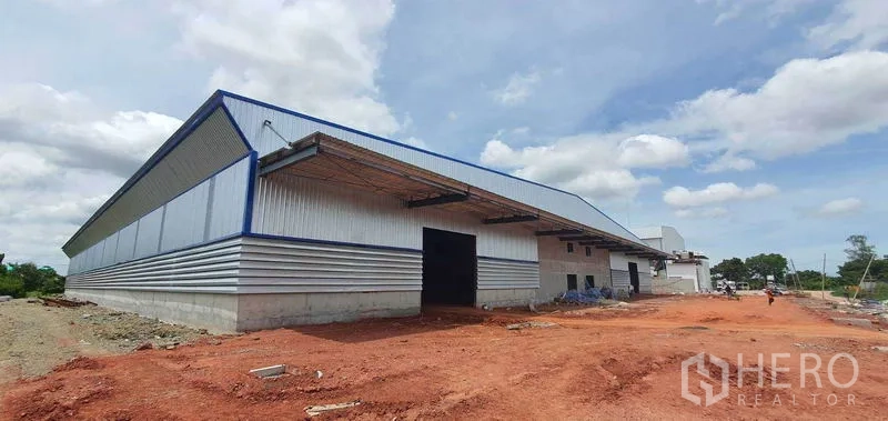 Factory for rent in Mueang Samut Sakhon, Samut Sakhon - Angled view of modern factory exterior with roller shutter doors, canopy awnings, and open yard area.