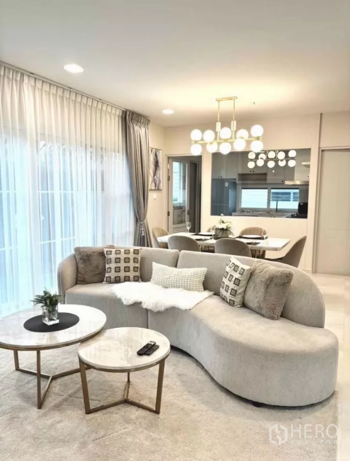 Detached House for rent in Bang Phli, Samut Prakan - Modern living room with a curved sofa, round marble tables and dining set.