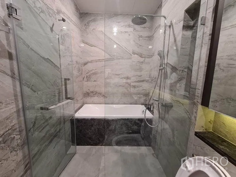Condominium for rent in Watthana, Bangkok - Glass-enclosed shower with rain head beside a soaking bathtub.
