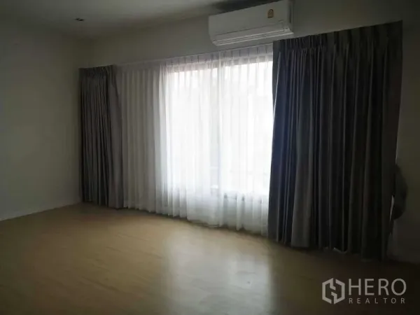 Home Office for rent in Bang Phli, Samut Prakan - Bedroom with wood flooring, large curtained window and wall-mounted air conditioner.