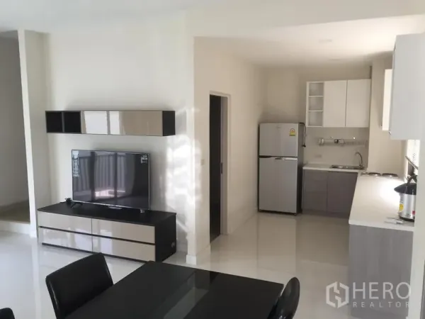 Townhouse for rent or sale in Saphan Sung, Bangkok - Fitted kitchen with upper cabinets, fridge and long countertop beside the living room.