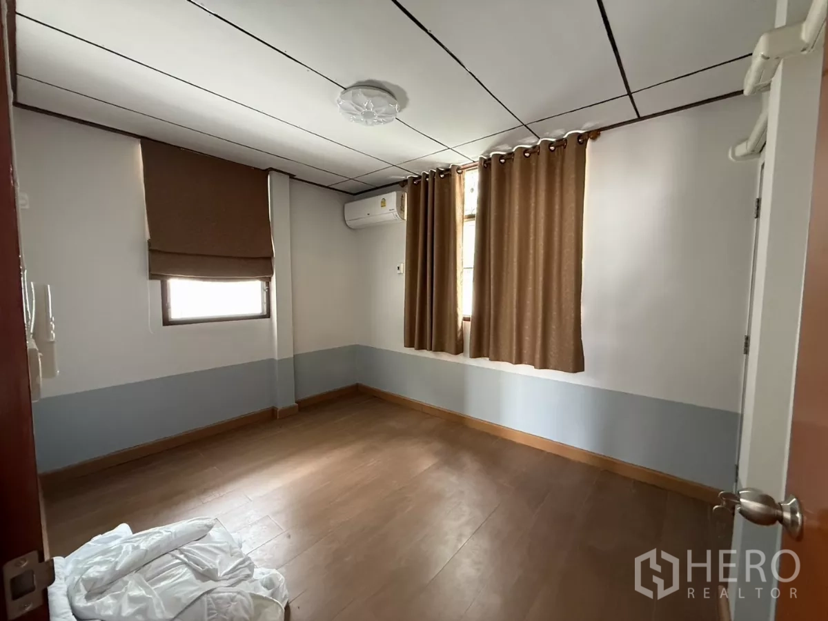 บ้าน ให้เช่าในPhra Khanong, Bangkok - ห้องนอนสว่าง พื้นไม้ แอร์ และหน้าต่างสองบานพร้อมผ้าม่าน.