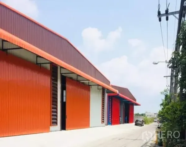 货栈 出租在Khan Na Yao, Bangkok - 曼谷坤那耀区一排橙色钢结构仓库，配大卷闸门与临街通道。