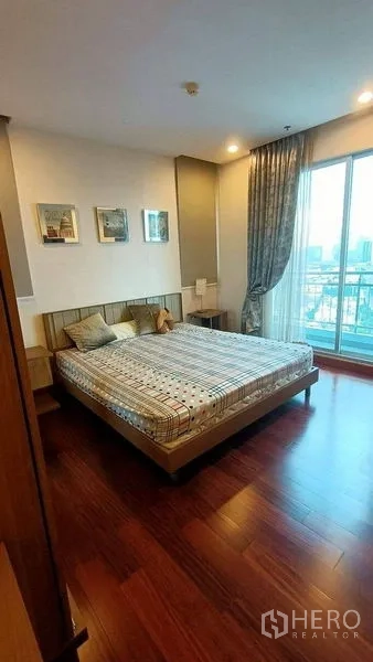 คอนโด ขาย - ห้องนอนใหญ่ พื้นไม้ หน้าต่างสูงจรดเพดานและวิวระเบียงเมือง