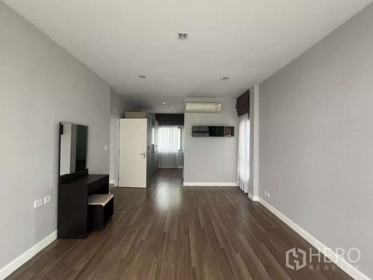 Detached House for sale in Bang Kapi, Bangkok - Large upstairs bedroom with wood floors, air conditioning, and ample light.