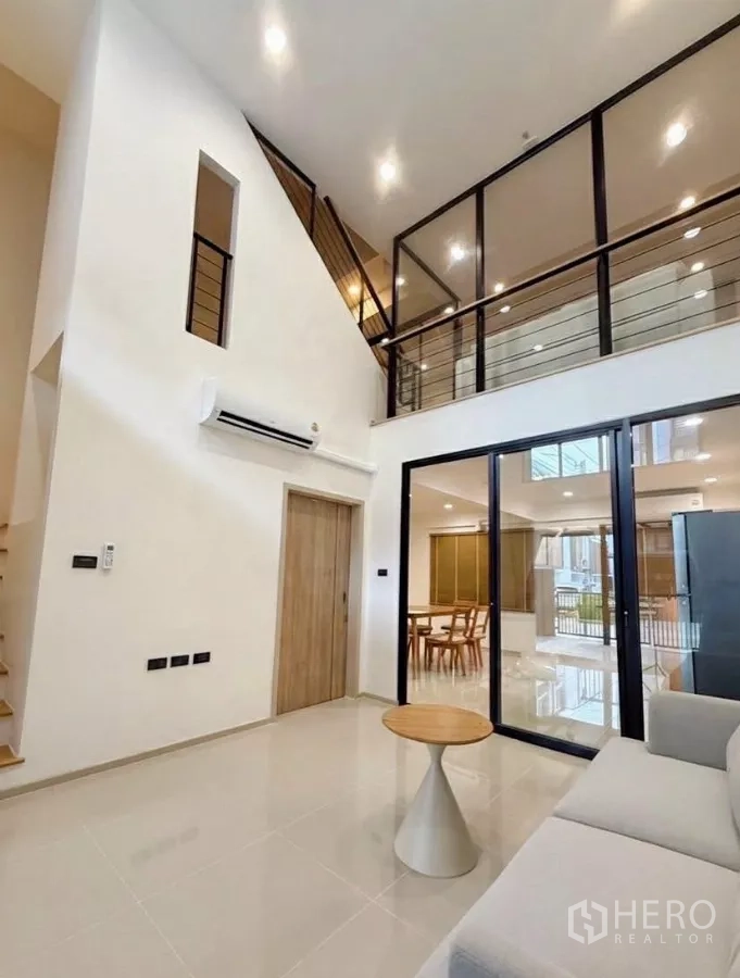 ทาวน์เฮาส์ ให้เช่าในSuan Luang, Bangkok - ห้องนั่งเล่นเพดานสูงเชื่อมชั้นลอย กั้นกระจกกรอบอลูมิเนียม