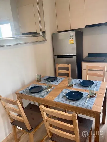 Condominium for rent in Huai Khwang, Bangkok - Dining area for four next to compact kitchen with fridge and cabinets.